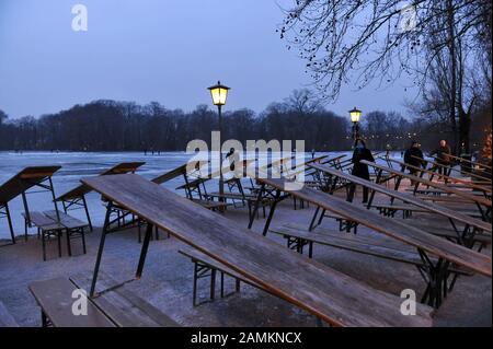 Abendatmosphäre im Seehauser Biergarten am Ufer des halbgefrorenen Kleinhesseloher Sees im Englischen Garten. [Automatisierte Übersetzung] Stockfoto