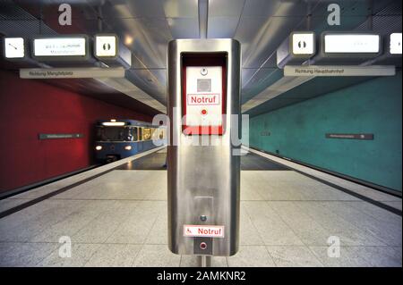 Notrufstelle im U-Bahnhof Wettersteinplatz, im Hintergrund eine ankommende U-Bahn. [Automatisierte Übersetzung] Stockfoto