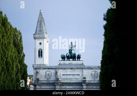 Siegestor und ein Turm der Ludwigskirche in der Münchner Maxvorstadt, von der Leopoldstraße aus gesehen. [Automatisierte Übersetzung] Stockfoto