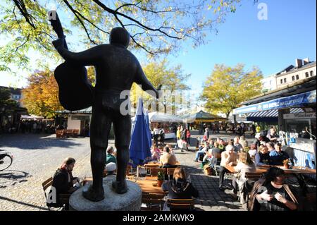 Gäste an einem warmen Herbsttag im Biergarten am Münchner Viktualienmarkt Im Vordergrund der Roider Jackl Brunnen. [Automatisierte Übersetzung] Stockfoto