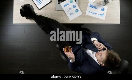 Erfolgreiche Investoren sehen Projektbericht, telefonieren, Cognac trinken Stockfoto