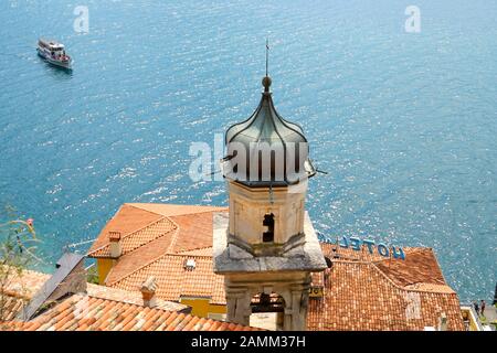Die Kirche 'San Rocco' vor einem Ausflugsboot in Limone sul Garda am Westufer des Gardasee. [Automatisierte Übersetzung] Stockfoto