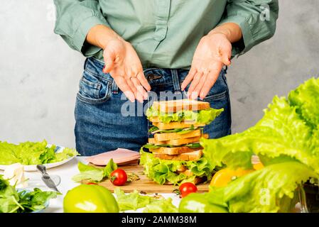 Frau hält einen Stapel Sandwiches in ihren Händen in der Küche Stockfoto