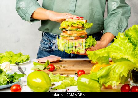 Frau hält einen Stapel Sandwiches in ihren Händen in der Küche Stockfoto