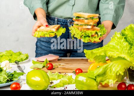 Frau hält einen Stapel Sandwiches in ihren Händen in der Küche Stockfoto