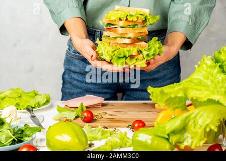 Frau hält einen Stapel Sandwiches in ihren Händen in der Küche Stockfoto