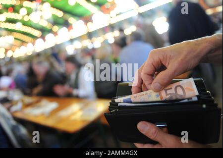 Eine Wiesn-Kellnerin verstaucht beim Oktoberfest Banknoten in ihrer Brieftasche in einem Bierzelt. [Automatisierte Übersetzung] Stockfoto