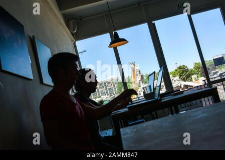 Jungunternehmer auf ihren Laptops im Café in Werk 1 in der Grafinger Straße 6 hinter dem Ostbahnhof. Im Hintergrund die Bauarbeiten für das Neubauviertel auf dem ehemaligen Pfanni-Gelände. [Automatisierte Übersetzung] Stockfoto