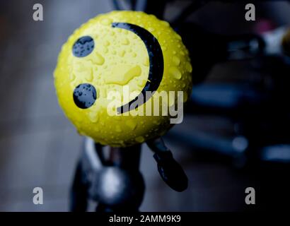 Am Münchner Hauptbahnhof lächelt ein Smiley auf einer Fahrradglocke trotzig über den Regen. [Automatisierte Übersetzung] Stockfoto