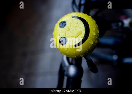 Am Münchner Hauptbahnhof lächelt ein Smiley auf einer Fahrradglocke trotzig über den Regen. [Automatisierte Übersetzung] Stockfoto