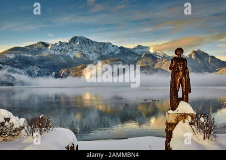 Herzogstand 1.731 m mit Kochelsee, frühmorgens, teils Nebel, Schnee auf dem Gipfel, vor der Skulptur Fischerjung - Fischer vom Kochelsee, die erstmals 1952 aus einer Drahtkonstruktion mit Putz und Ton errichtet wurde, die vom Bildhauer Prof. Richard Miller geschaffen wurde, Renoviert und vor einigen Jahren von Oswald Rifesser aus St. Ulrich in Tyrol, 10.01.2017 [automatisierte Übersetzung] Stockfoto