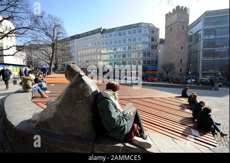 Am Springbrunnen am Rindermarkt genießen die Menschen die wärmende Wintersonne. Im Hintergrund der Löwenturm. [Automatisierte Übersetzung] Stockfoto