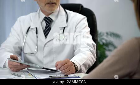 Arzt im Gespräch mit dem Patienten, Tablette mit Analysedaten, Diagnose Stockfoto