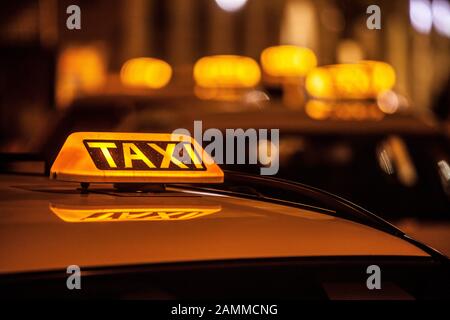 Die Taxis warten nachts in München mit beleuchteten Schildern für die Kunden. [Automatisierte Übersetzung] Stockfoto