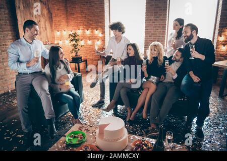 Foto des Feierns Gruppe Freunde, die die Überraschung Baby Party zukünftigen Eltern sofa großen Kuchen Getränke Sekt sitzen sagen Toast formalwear Verschleiß Stockfoto