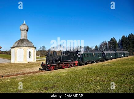 Bayerischer Lokalbahnverein Tegernsee, Federdampf, Sonderfahrt mit der Kohle-Dampflok 70 083 von 1913 von Tegernsee nach Holzkirchen und zurück, hier beim Überqueren der Bürgermeister-Erl-Straße neben der katholischen Kapelle St. Sylvester, einem sogenannten Freikirchl, in Hirschstätt bei Schaftlach, 12.03.2017 [automatisierte Übersetzung] Stockfoto