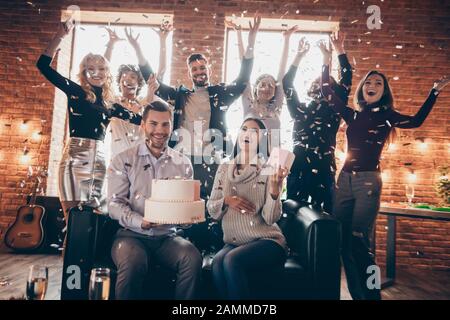 Foto der Gruppe funky beste Freunde organisieren überraschung Baby Party zukünftigen Eltern großen Stück Kuchen ovation Konfetti bringen fallenden Verschleiß formalwear Stockfoto