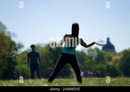 Eine Frau und ein Mann spielen an einem Frühlingstag im Englischen Garten mit einer Frisbee. [Automatisierte Übersetzung] Stockfoto