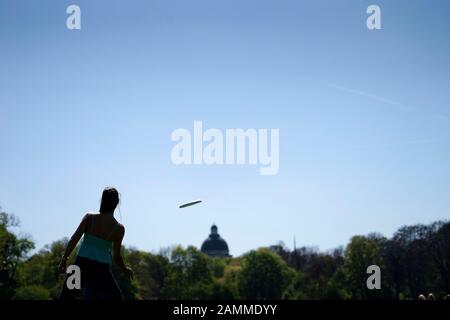Eine Frau und ein Mann spielen an einem Frühlingstag im Englischen Garten mit einer Frisbee. [Automatisierte Übersetzung] Stockfoto