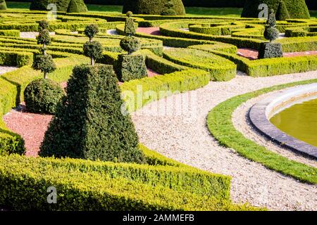 Ein Parterre in einem französischen Garten, mit Sträuchern und niedrigen Hecken aus Box Tree in geometrischen Formen geschnitten, und ein weißer Kies weg um ein Waschbecken. Stockfoto