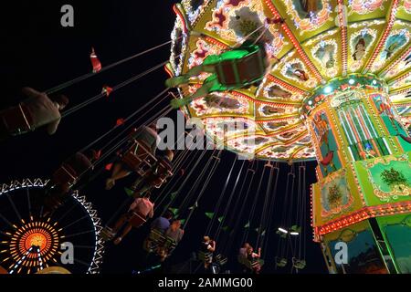 Kettenkarussell und Riesenrad auf der nächtlichen Theresienwiese. [Automatisierte Übersetzung] Stockfoto