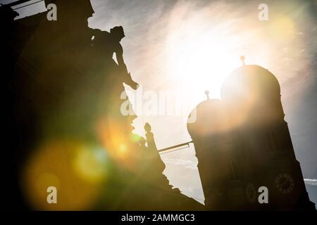 Die Türme des Liebfrauendoms in der Abendsonne, fotografiert von der Kardinal-Faulhaber-Straße. Die Statue im Vordergrund steht auf dem Dach der Bayerischen Hypotheken- und Wechselbank. [Automatisierte Übersetzung] Stockfoto