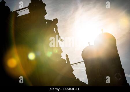 Die Türme des Liebfrauendoms in der Abendsonne, fotografiert von der Kardinal-Faulhaber-Straße. Die Statue im Vordergrund steht auf dem Dach der Bayerischen Hypotheken- und Wechselbank. [Automatisierte Übersetzung] Stockfoto