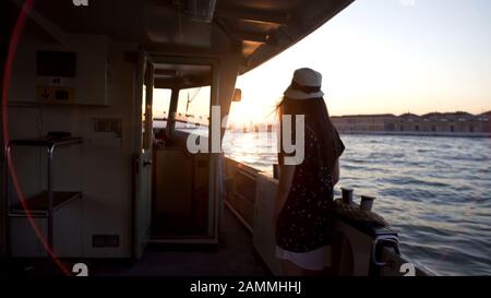 Einsame Touristin steht an Bord des Schiffes und betrachtet Venedig aus dem Wasser Stockfoto
