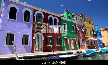 Bunte Häuser und Boote an Anlegestellen entlang des Kanals auf der Insel Burano Stockfoto