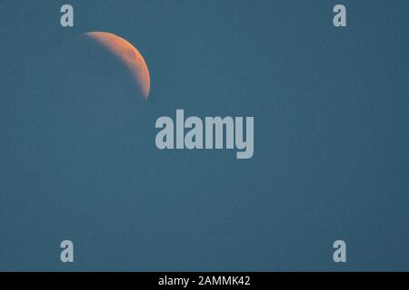 Vollmond während einer totalen Schattenfinsternis über München. Der Mond dringt vollständig in den Erdschatten ein, nur langwellige rote Lichtbestandteile erreichen ihn und er bleibt als sogenannter Blutmond schwach sichtbar. [Automatisierte Übersetzung] Stockfoto