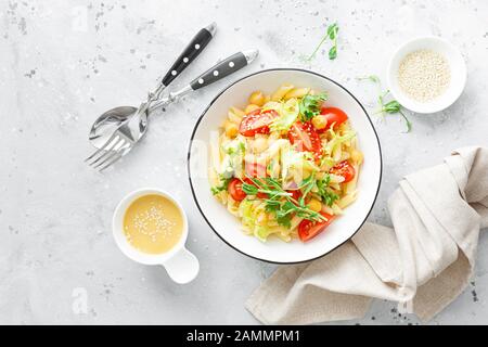 Nudelsalat mit frischer Tomate, Kichererbse, Salat und Erbsensprossen in der Mittagsschale Stockfoto