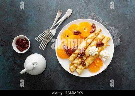 Crepes, dünne Pfannkuchen mit frischen Mandarinenscheiben, Pekannüssen, Sirup und Schlagsahne Stockfoto