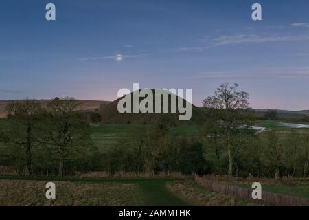 Der Planet Venus, der sich über dem riesigen neolithischen Kreidehügel von Silbury Hill erhebt, wird hier von Mondlicht gesehen. Er ist 40 m hoch und wurde um 2300 v. Chr. erbaut Stockfoto