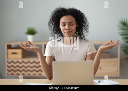 Afrikanische Frau meditiert am Schreibtisch vor dem Laptop Stockfoto