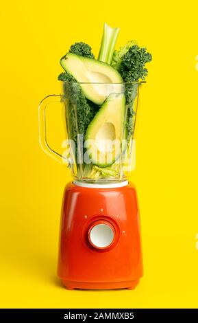 Smoothie-Rezept. Grüner Smoothie von Gemüse (Avocado, Sellerie, Salat, Spinat) in einem Mixer auf gelbem Hintergrund. Veganes und gesundes Essen detox Stockfoto