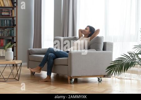 Die heitere afrikanerin lehnte sich auf der Couch auf, die zu Hause ruhte Stockfoto