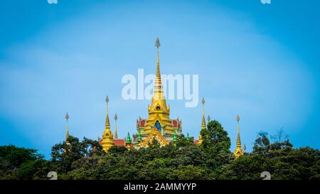 Thailändischer Tempel, der über den Bäumen mit klarem blauen Himmel in Ben Krut Thailand aufragt Stockfoto