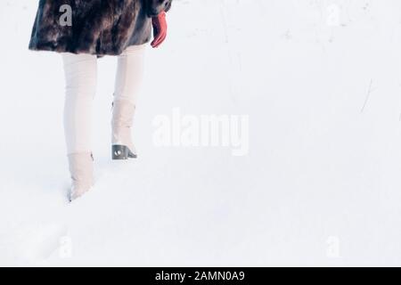 Nahaufnahme der Frauenfüße in Stiefeln auf weißem Schnee im Winter geht ein Mädchen auf dem Weg vorwärts Stockfoto