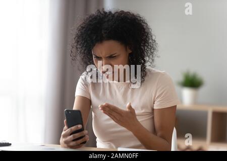 Afrikanische Frau, die Smartphone hält, sieht Bildschirmschwänne auf dem Gadget an Stockfoto