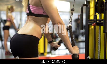 Junge blonde Frau, die in der Sporthalle arbeitet, Sportkörperform, Pull-down-Bewegung Stockfoto