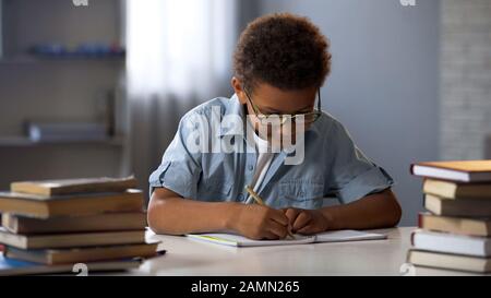 Clevere männliche Schüler, die mathematische Hausaufgaben machen, Gleichsetzung in Notizbuch lösen, Wissen Stockfoto