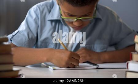 Grundschüler schreiben eifrig Briefe in sein Notizbuch, Kalligraphie Stockfoto
