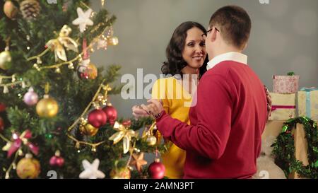 Glückliches Paar in der Liebe tanzt in der Nähe des Weihnachtsbaums und feiert gemeinsam Neujahr Stockfoto