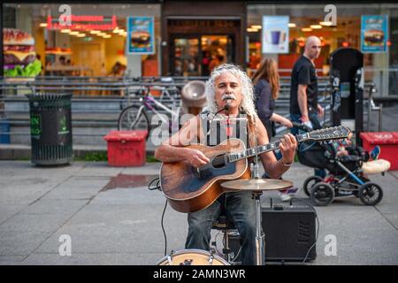 Oslo, Norway-1. August 2013: Ein Straßenmusiker tritt auf der Hauptstraße von Karl Johans Tor auf. Diese Straße ist eine der belebtesten in der Stadt, voller Stockfoto