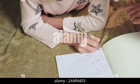 Schlaue Mädchen lösen mathematische Gleichungen im Bett, Homeschoolbildung Stockfoto