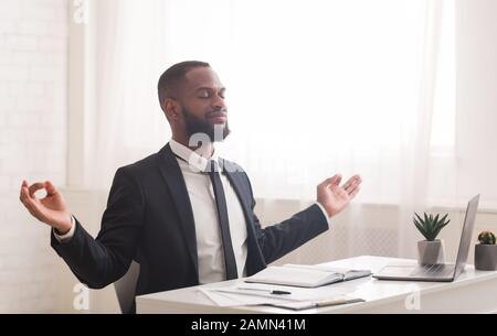 Junger Geschäftsmann, der im Büro meditiert und sich während der Arbeit entspannt Stockfoto