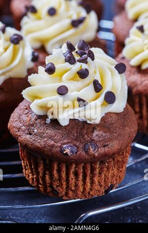 Nahaufnahme von Schokoladenkuchen mit Vanillebuttercreme-Verwirbelung auf einem Metallkuchengestell auf einem Betontisch, horizontale Ansicht von oben Stockfoto