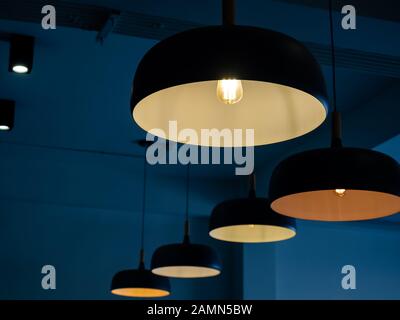 Schöne runde, moderne Deckenlampen mit Glühbirnen im dunkelblauen Raumhintergrund. Stockfoto