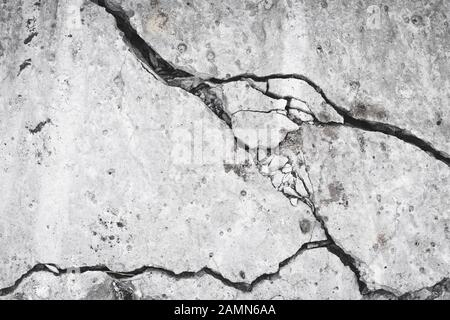 Zerstörte Betonwand, Riss und Löcher in der Zementplatte. Grunge Oberfläche, Gefahrenkonzept. Schadenswirkung, Textur. Grauer Steinhintergrund, Material Stockfoto