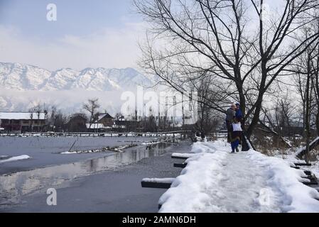 Eine Kaschmiri-Frau läuft nach dem frischen Schneefall in Srinagar auf schneebedeckte Holzbrücke.Aufgrund der starken Schneefälle in den letzten 48 Stunden gab es mehrere Lawinen, in denen mindestens 4 indische Armeesoldaten und 5 Zivilisten Im indianischen Kaschmir ermordet wurden. Stockfoto